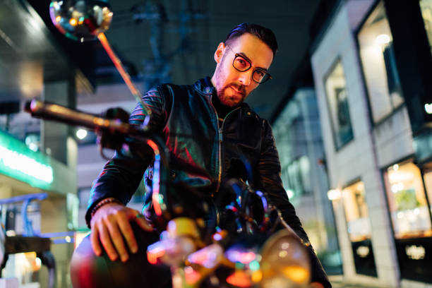A portrait of a handsome male motorbike rider in the street at night.